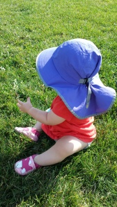 Sunday Afternoons Playhat  being used while exploring the grass. You can see it cinches to make a tight fit.